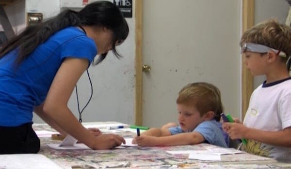 A 2012 Art Camp intern works with students. Watch the video .