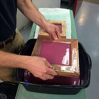 Yoder dunks this frame into a tub of watery pulp, then drains the water. The pulp settles to create a wet square of paper, which needs to dry.