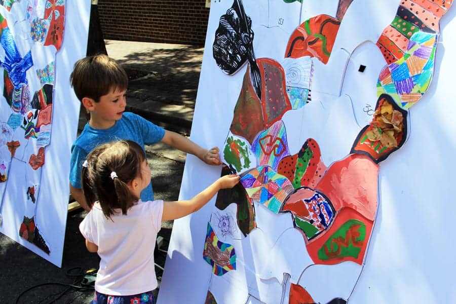 Placing a completed piece in the community puzzle art project.